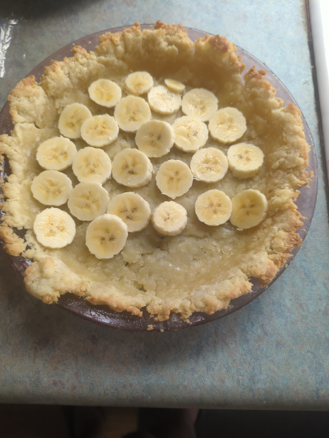 photo of a baked pie crust with a partial layer of sliced bananas in it