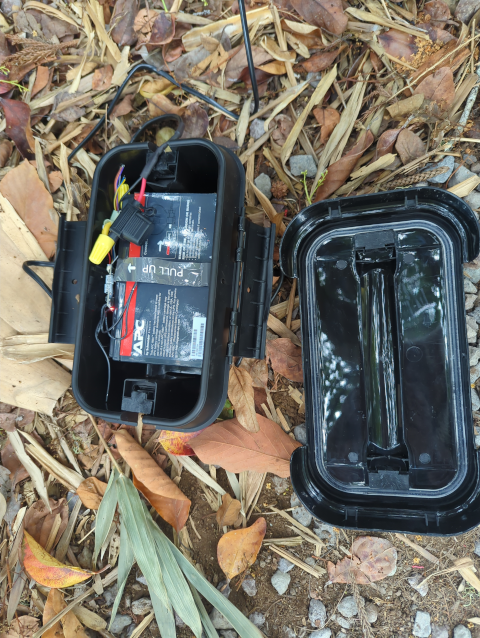 photo of a weatherproof box with a lead-acid gel battery and a Shelly Plus Uni monitor tucked inside