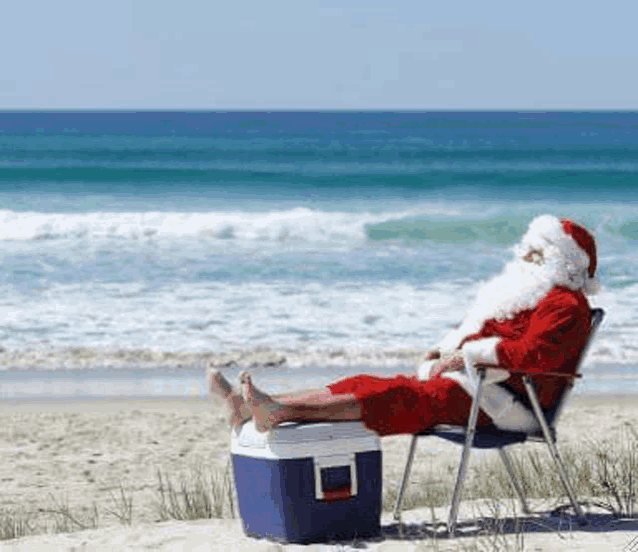 stock photo of a man wearing Santa Claus garb, but with his bare feet up on a cooler at the beach