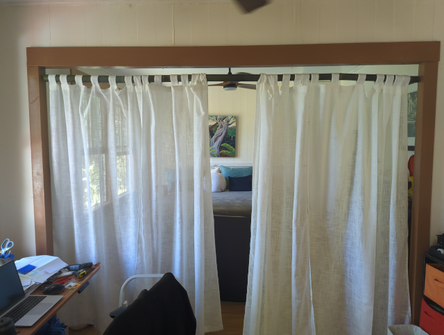 photo of white curtains hanging from a bamboo rod closing off our bedroom