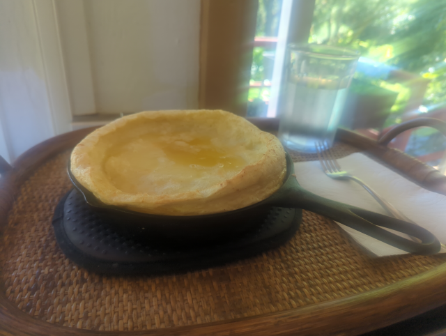 photo of a cast-iron skillet with a cooked batter in it, rising over the edges at the rim but depressed in the center