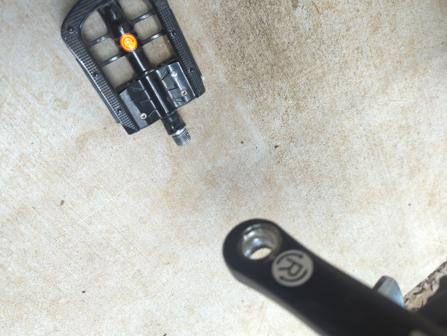 photo of the right pedal of my ebike lying on the ground next to the crank; the threads in the crank are stripped out