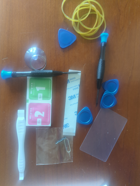 photo showing a repair kit with two screwdrivers, four spudgers, rubber bands, some 3M tape, a screen cleaner, and a suction cup