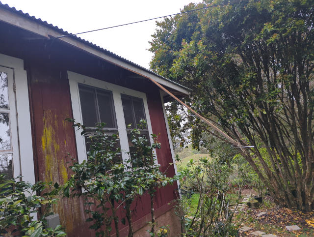 photo of the side of the house with a chunk of fascia torn away with the cable dangling from it.