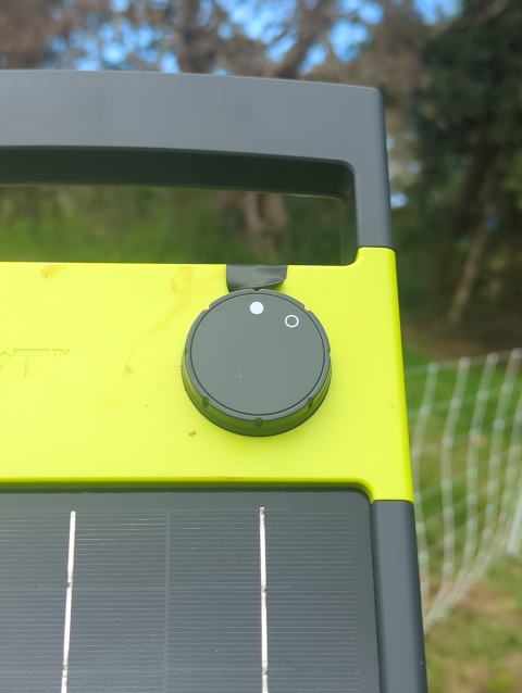 photo of the fence charger, close-up on the on-off knob and the indicator light above it, which has been covered with a flap of black electrical tape