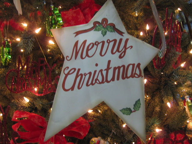 photo of a fabric ornament on a Christmas tree that says "Merry Christmas"