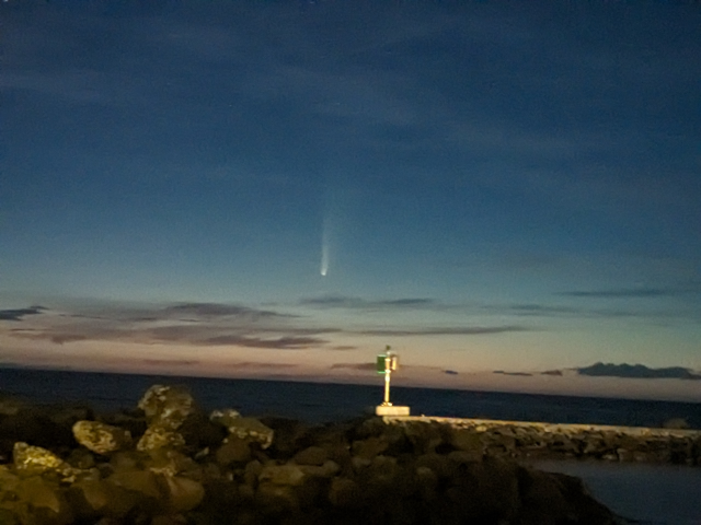 photograph of a comet, looking out over the ocean at a harbor taken with night mode