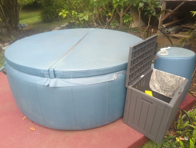 photo of a blue hot tub with a brown deck box next to it