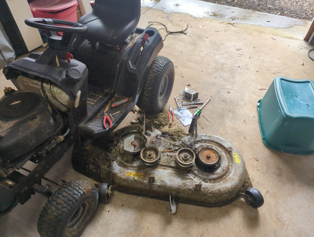 photo of the Murray MT100 with the mowing deck removed; the stringy remnants of a shreddeed belt are visible in the background
