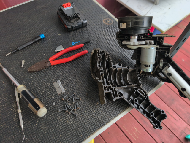 photo showing the disassembled string trimmer along with some tools and a pile of screws