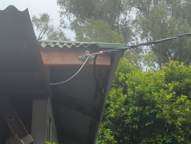 photograph of the corner of the house, with a new fascia board and an overhead feeder attached