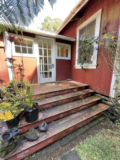 photo of the front porch of the house before we bought it showing a lot of rotting fascia and many potted plants on the steps hiding their disrepair