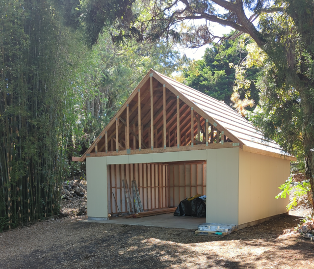 a photo of a garage under construction, with no siding between the top of the walls and the roof