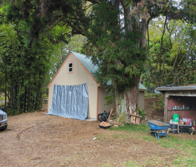 photograph of the new garage with a silver tarp hanging over the door as a protective curtain