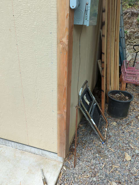 photo of the service panel for the garage, with a heavy-gauge copper wire leading to a copper ground rod