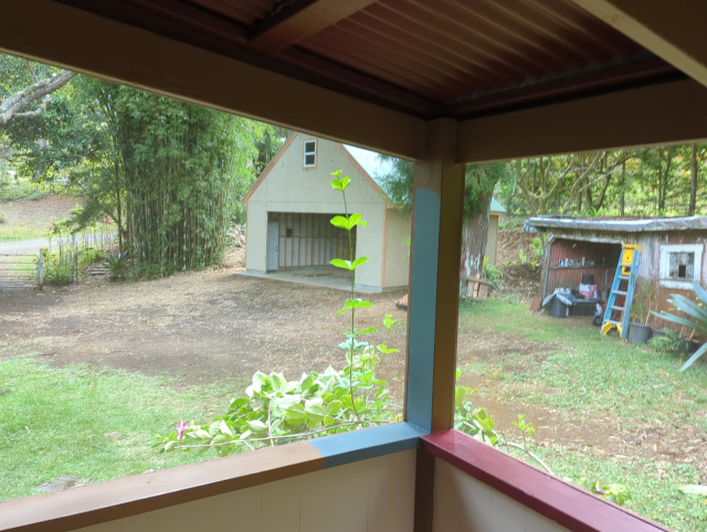 photograph from inside the screened-in lanai which shows our main gate, the new garage sans door, and the old garage