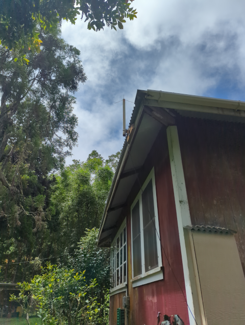 photo showing a quarter-wave vertical GMRS antenna mounted on the eaves of the house, high in the sky