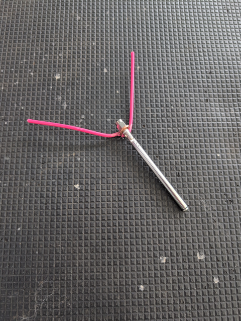 photo showing a telescoping whip antenna with a wire crudely bent around its base to form two ground-plane radials tapered at 45°