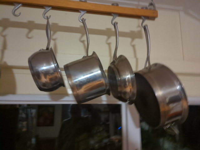 photo of a hanging pot rack with a medium-size stainless steel saucepan centered in the frame