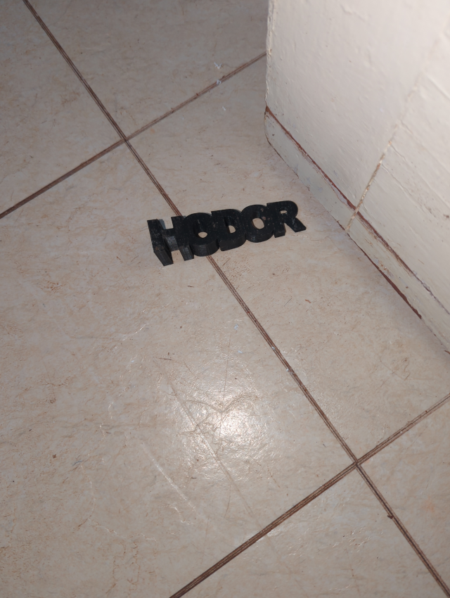 photo of a 3-D printed door stop that spells "HODOR"