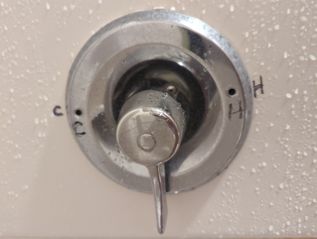 photo of a shower control handle with H scrawled in permanent marker on the wall and fixture on the right and C, similarly, on the left