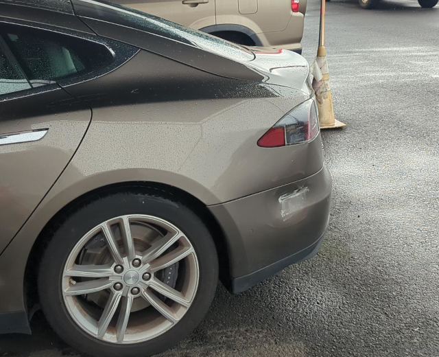 photograph of the read quarter panel of a car with a large dent and scratch in the rear bumper