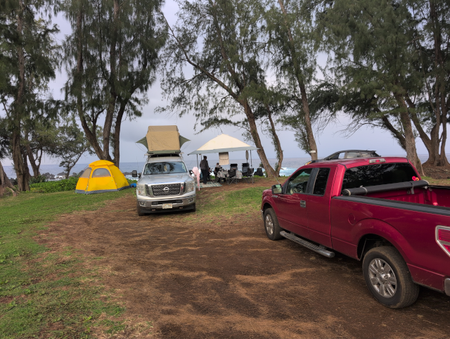 photo showing Timmy the Titan with tent on top deployed, canopy tent, and dome tent set up with HA, L, & C looking out at the Pacific Ocean