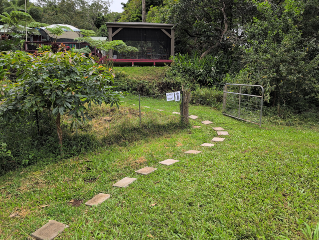 photo looking at the middle gate; next to the middle gate is a sign that says "ALMOST THERE!" and an arrow pointing up toward the pavilion and the house