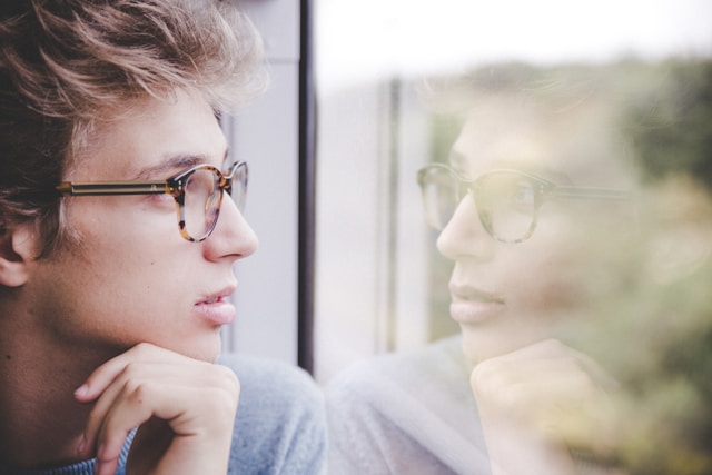 photo of a man looking at his reflection in a window