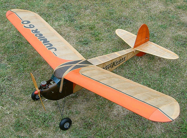 photo of a hand-painted wooden model airplane parked on grass