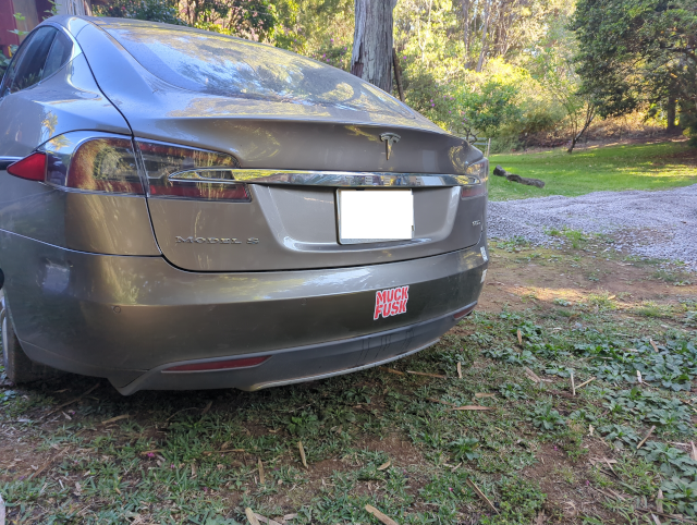 photo of an older Tesla Model S with a "muck fusk" bumper sticker