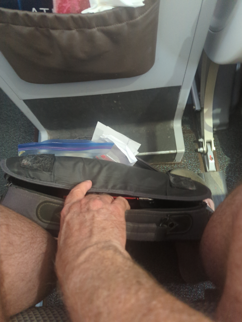 photo of my feet crammed into a space where they don't fit with my laptop bag resting on top of them