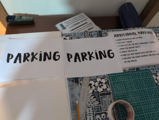 photo showing two "parking" signs ready to be laminated; an "additional parking" sign is partially obscured to the right