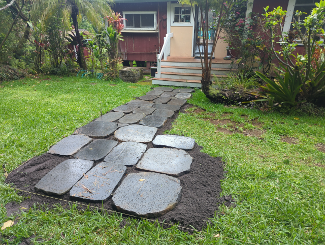 photo looking toward the front door; the stone path from the front steps is complete to where it turns toward the driveway; the old stone path has been removed; everything is wet