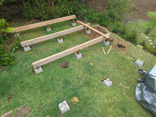 photo showing a deck under construction, with 4x8 beams set on precast concrete piers with 4x4 risers