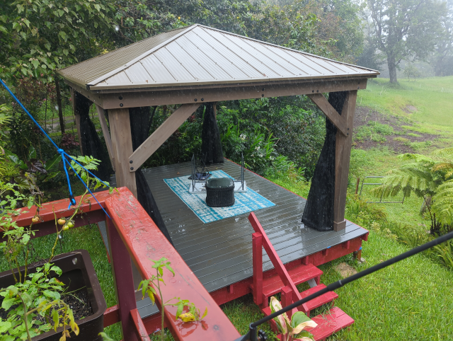 photo of the pavilion showing the mosquito nets tied back, most of the furniture removed, and the remaining set down in the middle of the structure