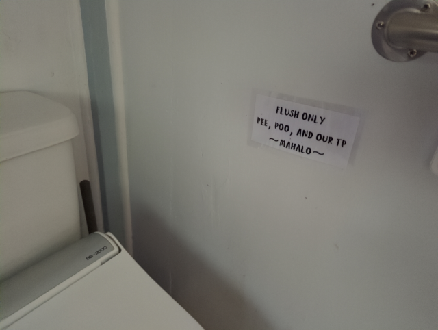 photo showing a sign by a toilet that reads "flush only pee, poo, and our TP mahalo"