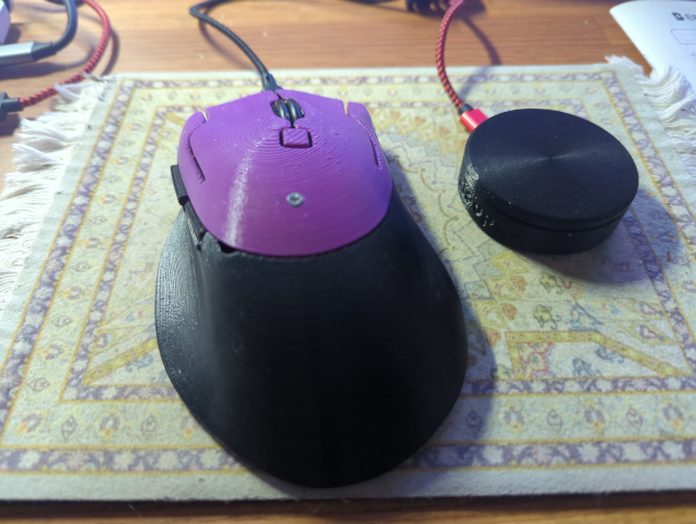 photo of a purple Ploopy mouse and a black Ploopy knob on a Persian-carpet themed mousepad