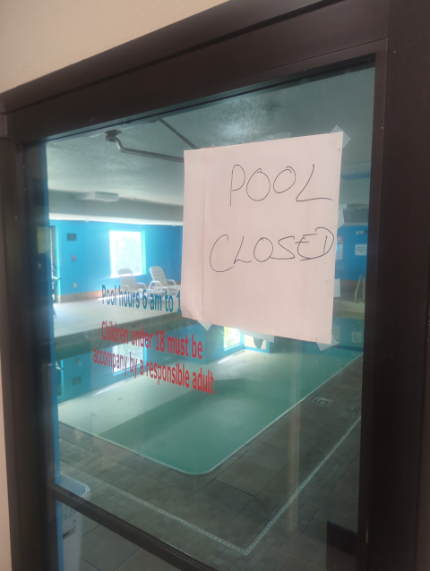 photo of a sign on the door to a motel pool with a handwritten "Pool Closed"