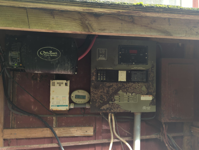 photo of a decade-plus old inverter and some rusty, dilapidated electrical service panels