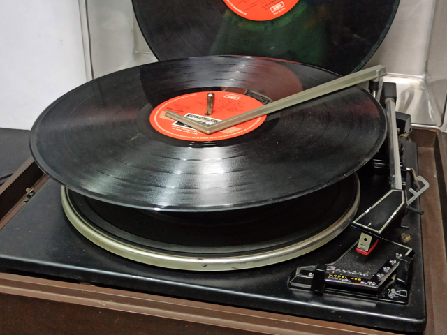 photograph of a record changer with an LP ready to drop on the turntable