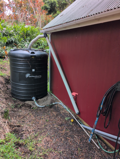 photo showing our catchment system; the water tank had developed a lean toward the garage, but it is once again vertical now