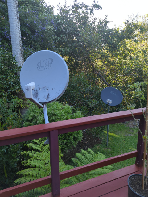 photo of two satellite dishes, one mounted to a deck railing and the other on a dedicated mast