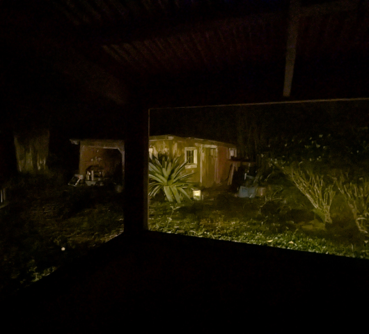 photo of the old shed as seen from our little lanai at night illuminated by landscape lights
