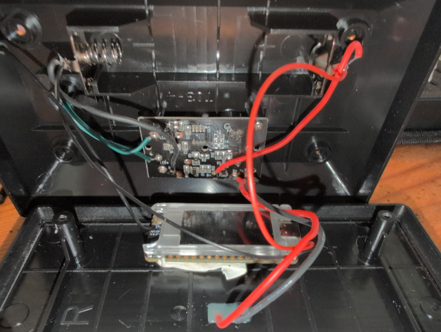 photo showing the T114 stuck in mounting putty and fine wires soldered to the battery holder terminals and leading to the T114