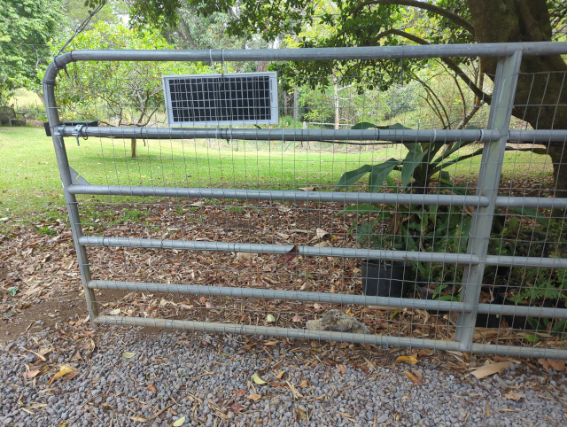 photo of a driveway gate with a solar panel mounted on it