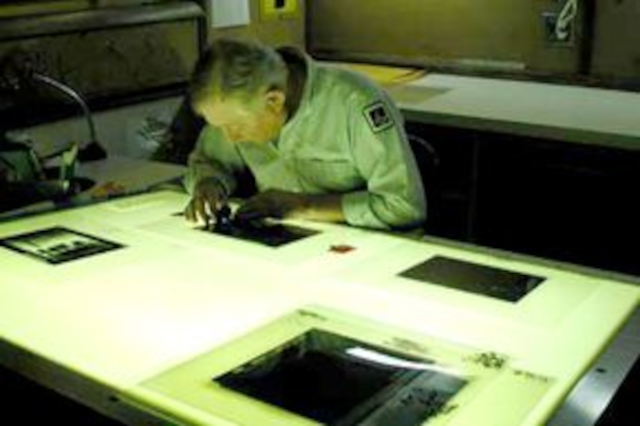 photo of a person at a light table arranging negatives for making printing plates