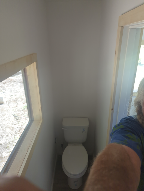 photo of the studio bathroom looking toward the toilet. The room is barely wide enough to fit the toilet in