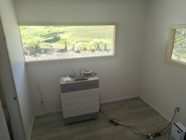 photo of the lower room of the studio, showing the solar battery stack and looking out the window at the solar panels