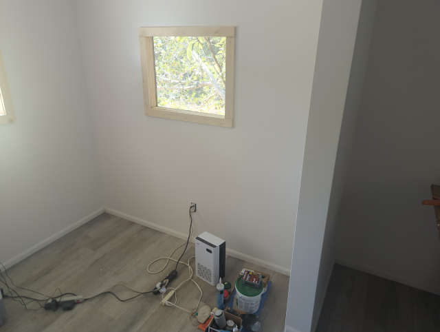 photo of the lower room of the studio looking out the little window; there are tools and a dehumidifier in the foreground